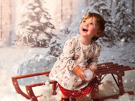 Fotoshooting, Kind im Schnee auf Schlitten